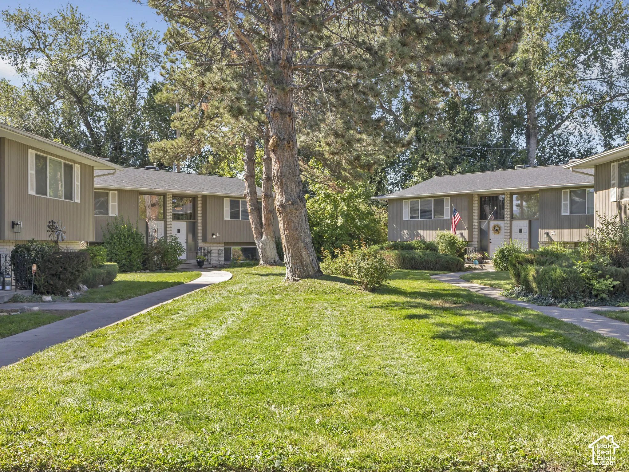 Expansive green lawn with mature trees and paved walkways