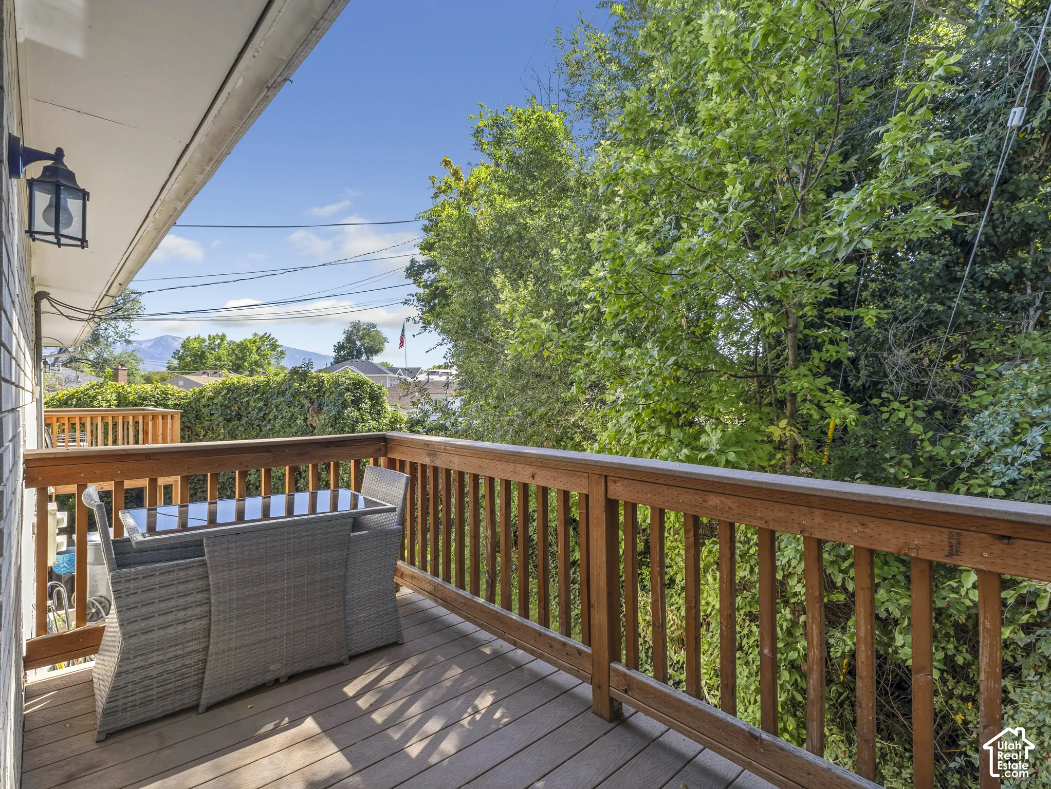Wood-plank deck with wood railing, featuring a mounted outdoor light fixture and overhead soffit