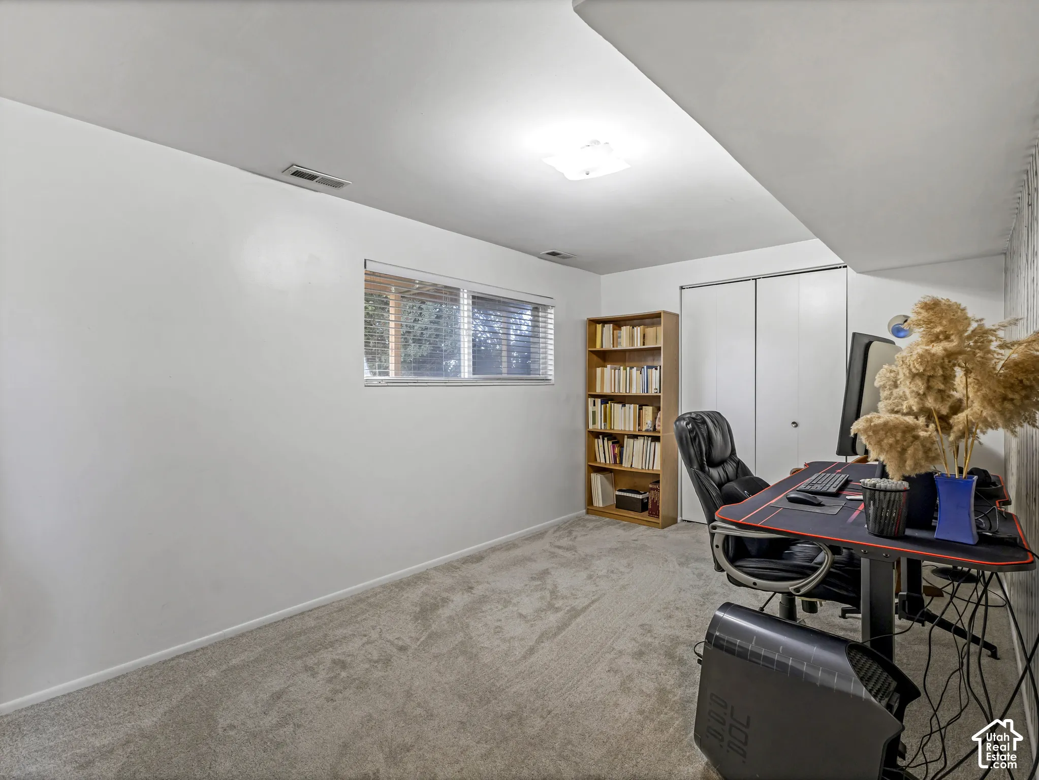 Carpeted room featuring a window with horizontal blinds, built-in closet with bi-fold doors, and a flush-mount ceiling light fixture