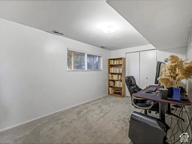 Carpeted room featuring a window with horizontal blinds, built-in closet with bi-fold doors, and a flush-mount ceiling light fixture