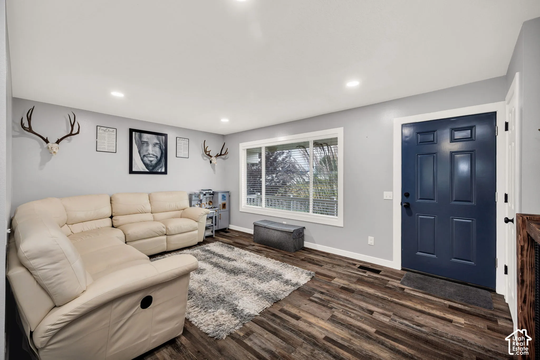 Recessed lighting throughout, wood-finish flooring, white window trim, and a paneled entry door with dark hardware