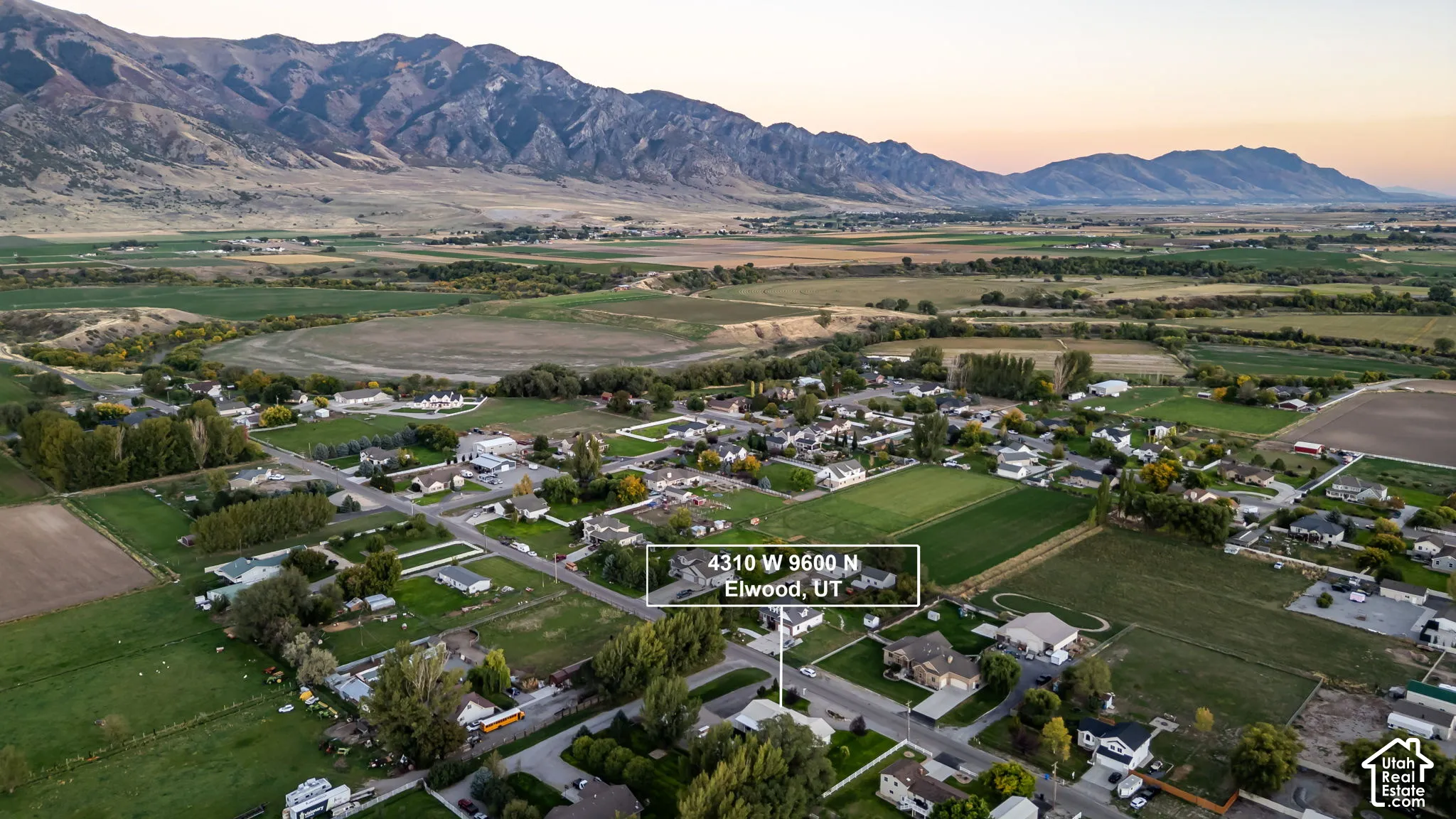 Rural residential setting with mountainous backdrop and cultivated fields