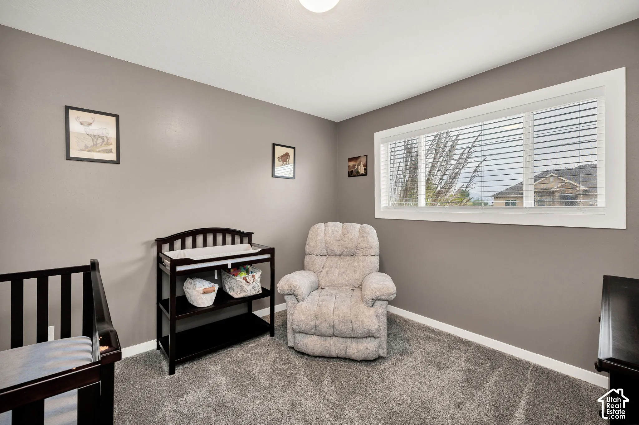 Neutral wall color, grey carpeting, a large window with white blinds, and white trim