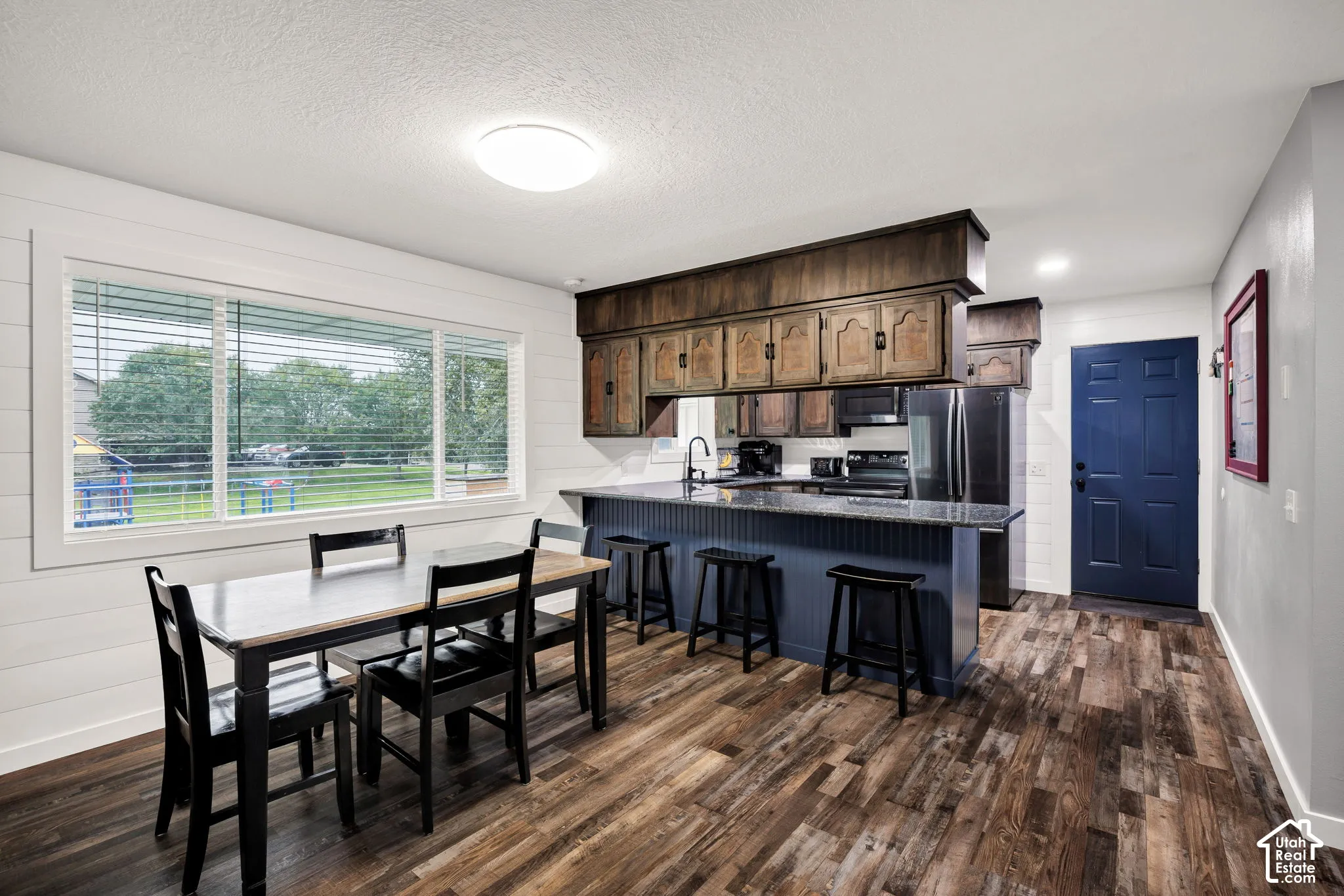 Kitchen with wood-finish flooring, dark wood cabinetry, and a central island with a contrasting blue base