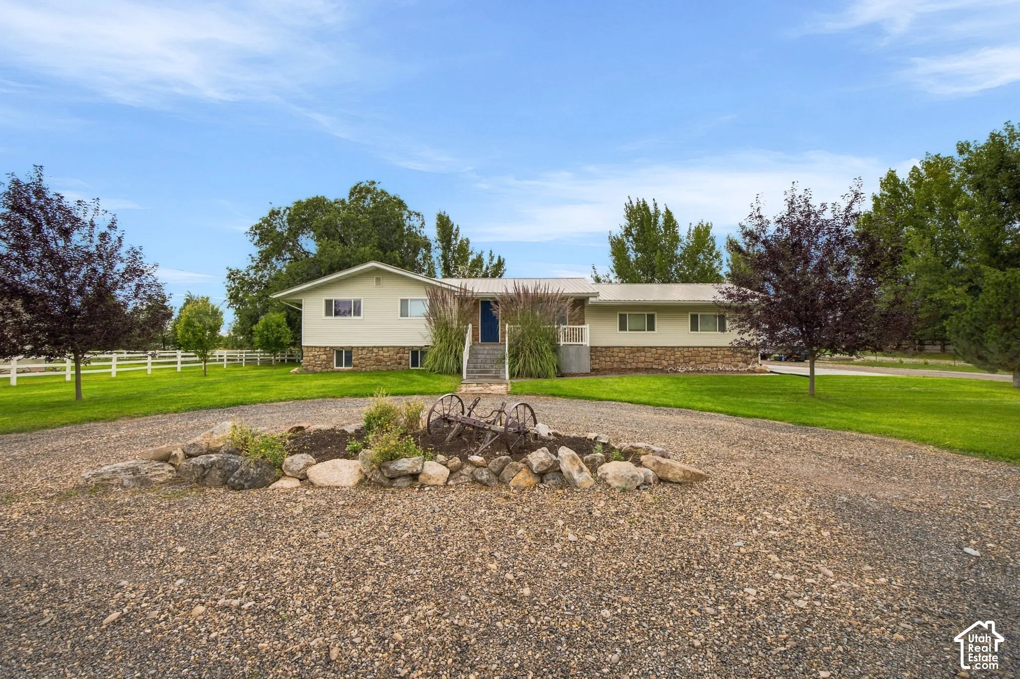 Split-level residence featuring stone and siding exterior, a circular gravel driveway, and a central rock garden