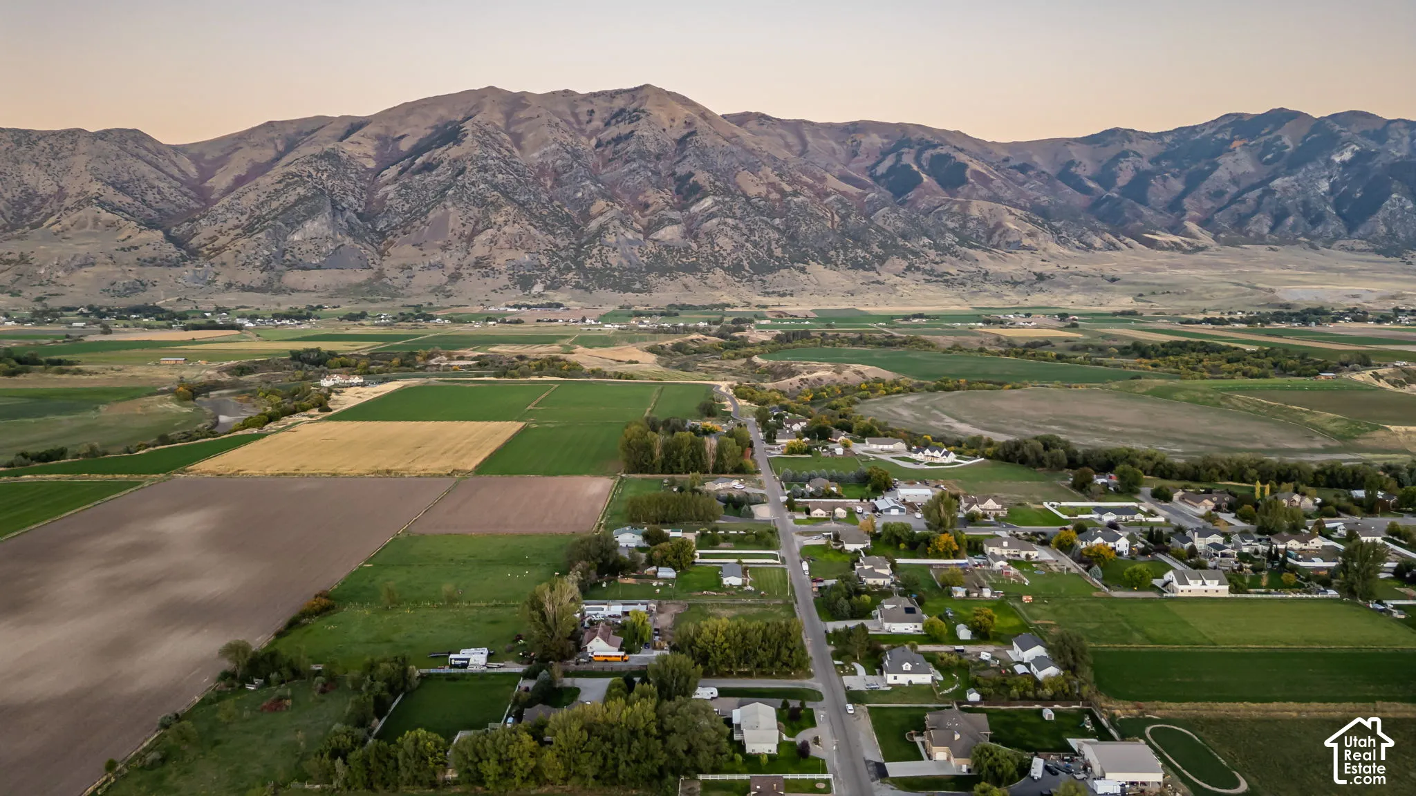 Mountain backdrop overlooking a rural community with agricultural fields and residential properties