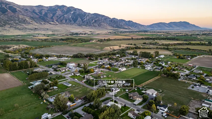 Rural residential setting with mountainous backdrop and cultivated fields