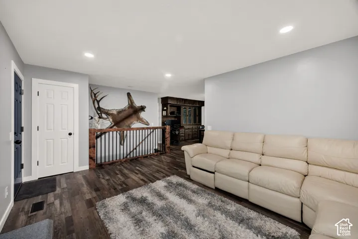 Wood-finish flooring, recessed ceiling lighting, and a dark wood and metal railing