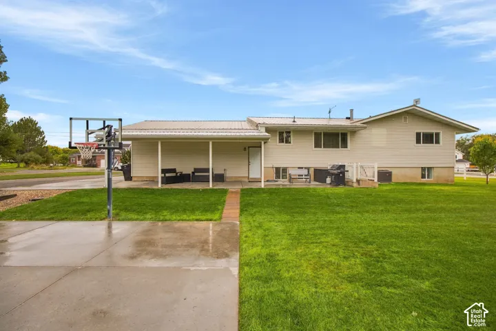 Expansive green lawn with a concrete patio, covered patio area, and concrete driveway