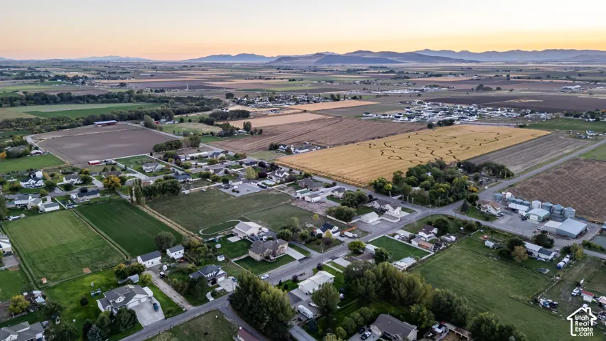Expansive agricultural fields, residential properties, and distant mountain ranges