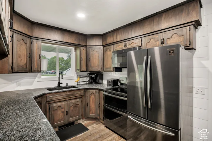 Kitchen featuring wood cabinetry, dark speckled countertops, stainless steel appliances, and a window above the sink