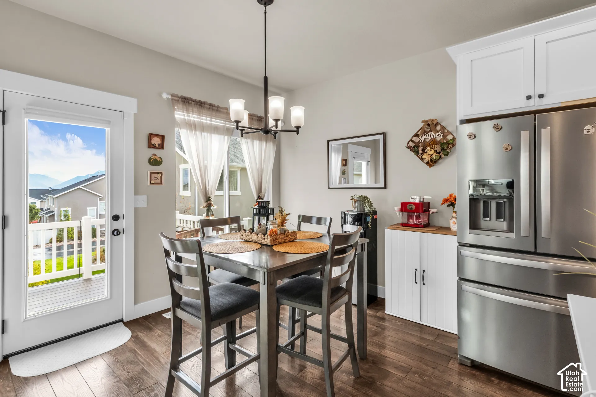 Wood-finish flooring, white cabinetry, stainless steel refrigerator, and a glass-paneled door leading to an outdoor deck