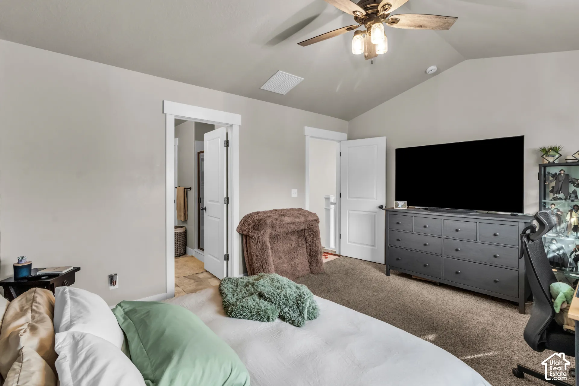 Vaulted ceiling with an attached ceiling fan, neutral wall paint, and carpeted flooring