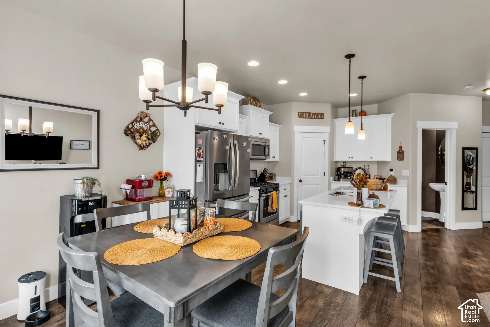 Open-concept kitchen and dining area featuring a central island, stainless steel appliances, white cabinetry, and wood-finish flooring