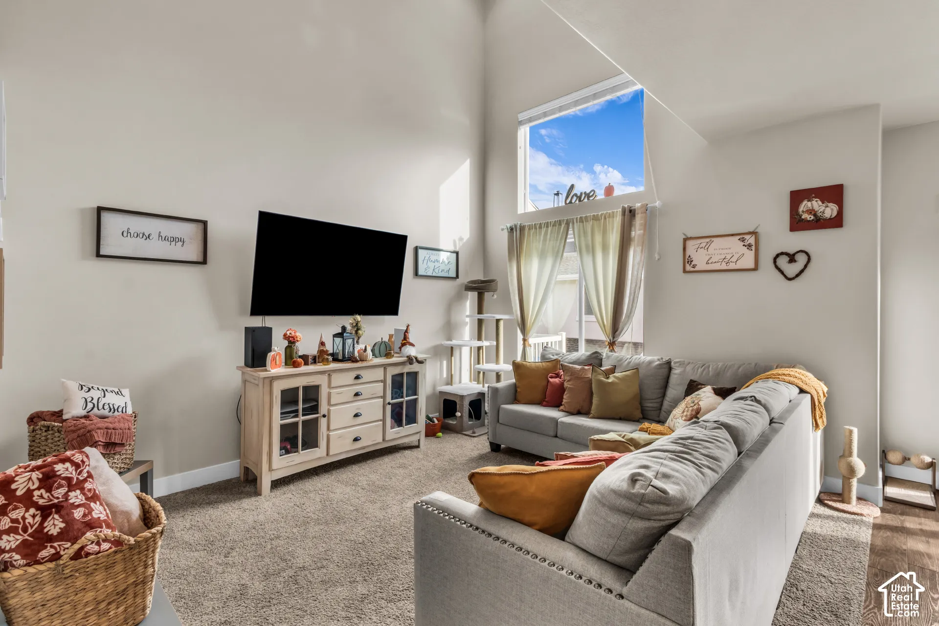 Vaulted ceiling, upper transom window, recessed media niche with wood-finish media console, neutral wall paint, and carpeted flooring