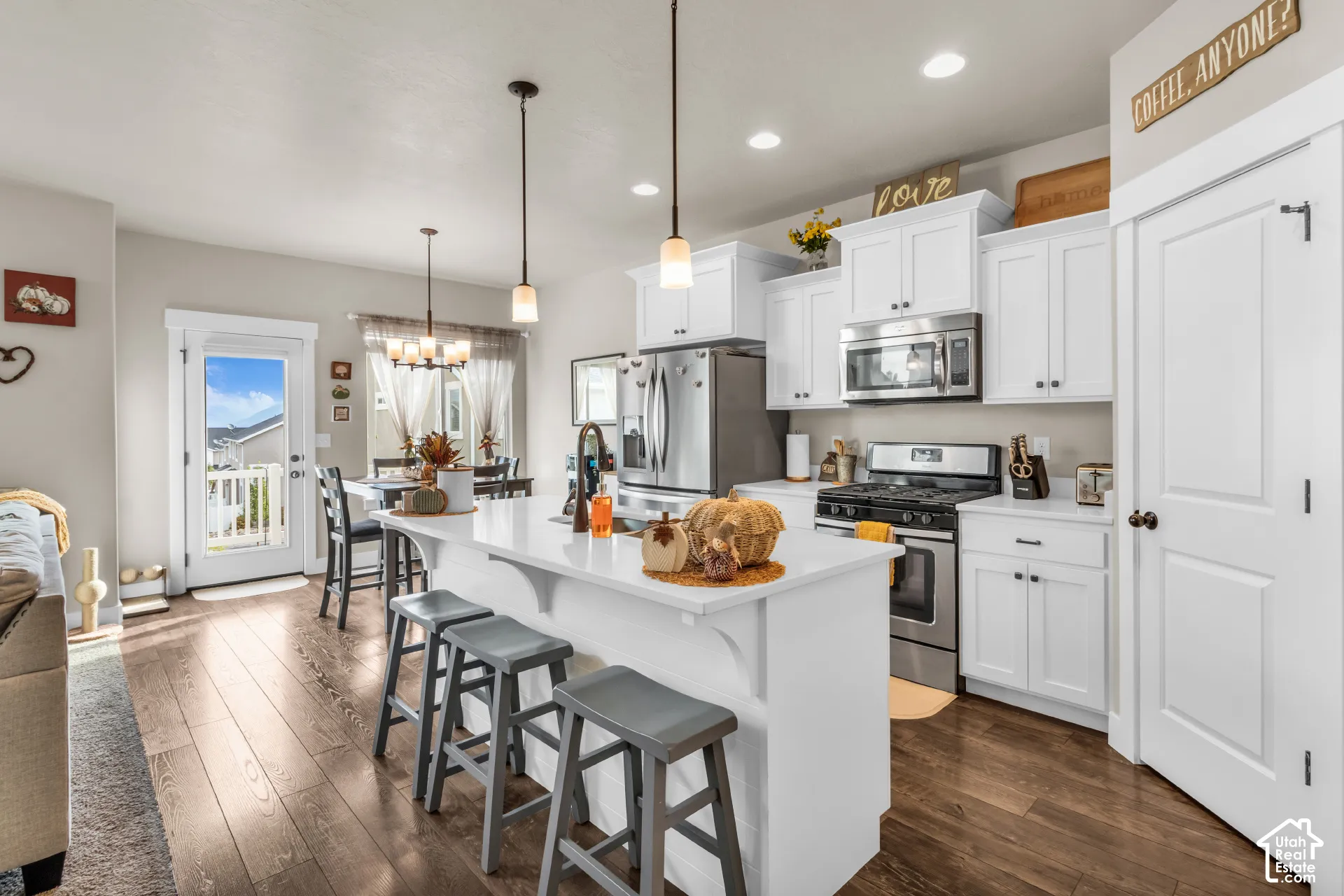 Kitchen featuring white cabinetry with brushed nickel hardware, stainless steel appliances, and a central island with countertop seating