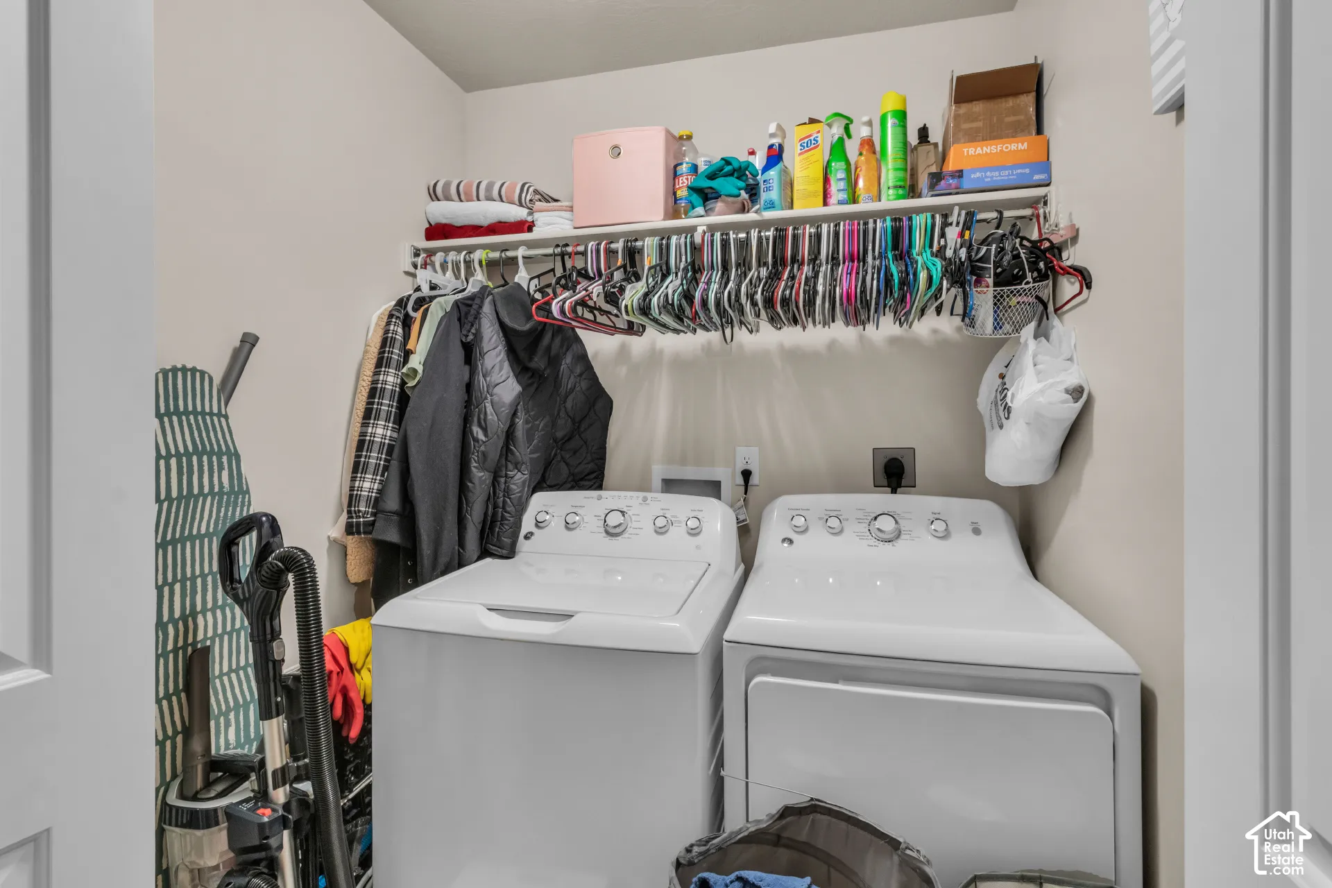 Laundry area featuring a built-in shelf, clothes hanging rod, and light neutral wall paint