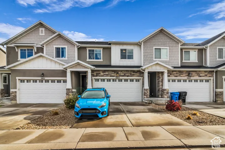 Contemporary townhome exterior featuring an attached garage, stone accents, and a covered entry