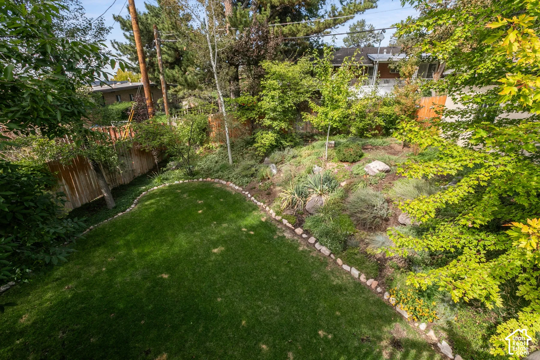 Expansive backyard featuring a manicured lawn, established landscaping, and a wooden perimeter fence