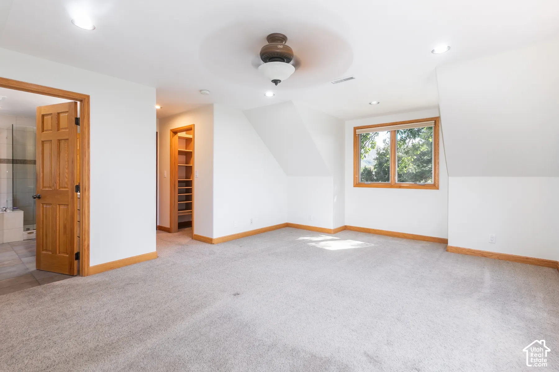 Carpeted room with recessed lighting, an angled ceiling, a ceiling fan, and a wood-framed window