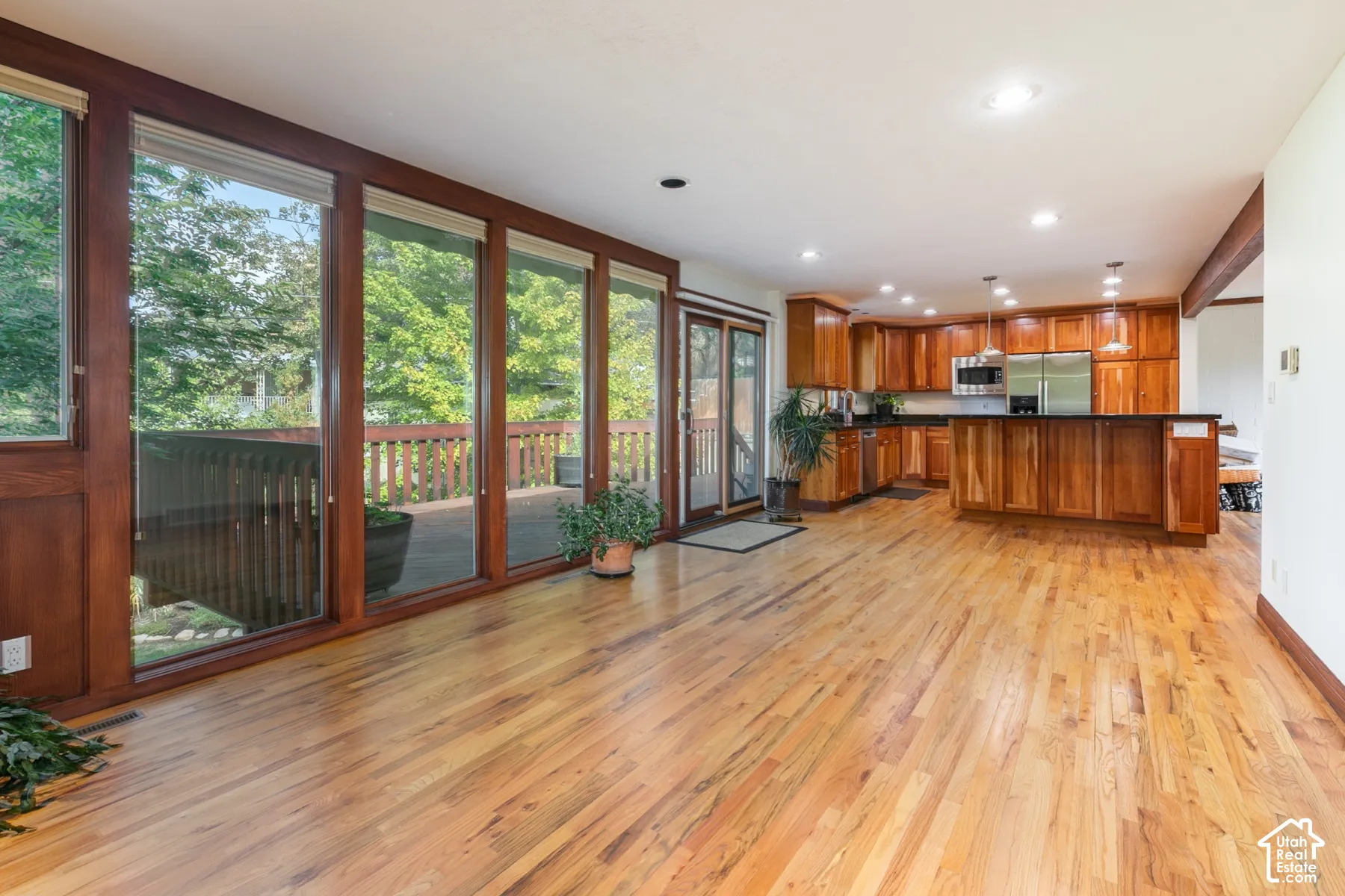 Hardwood flooring, wood-framed sliding glass doors, built-in wooden cabinetry, recessed lighting, and stainless steel appliances