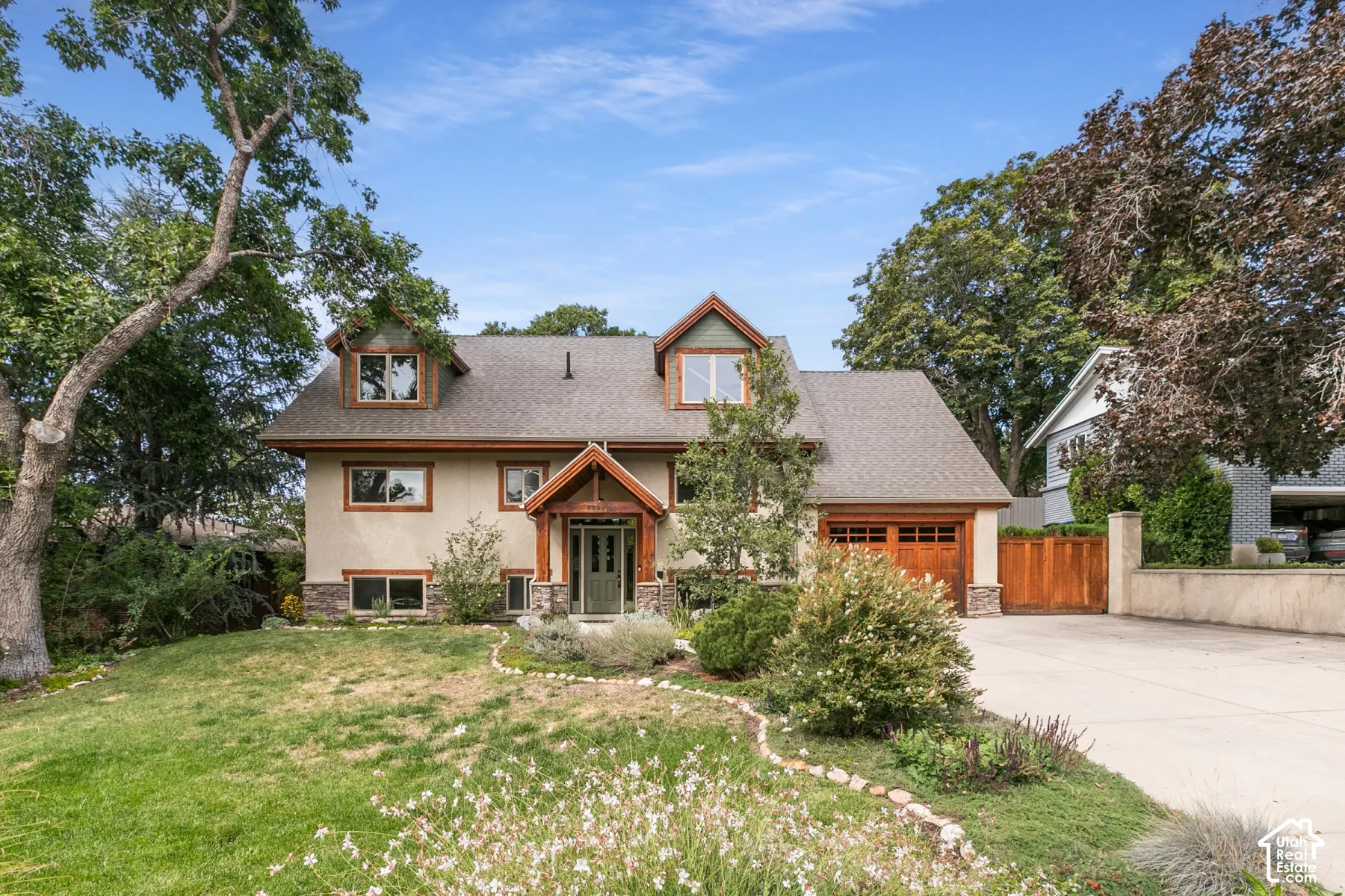 Stucco exterior with stone accents, wood-finish garage door, dormer windows, and a covered entry
