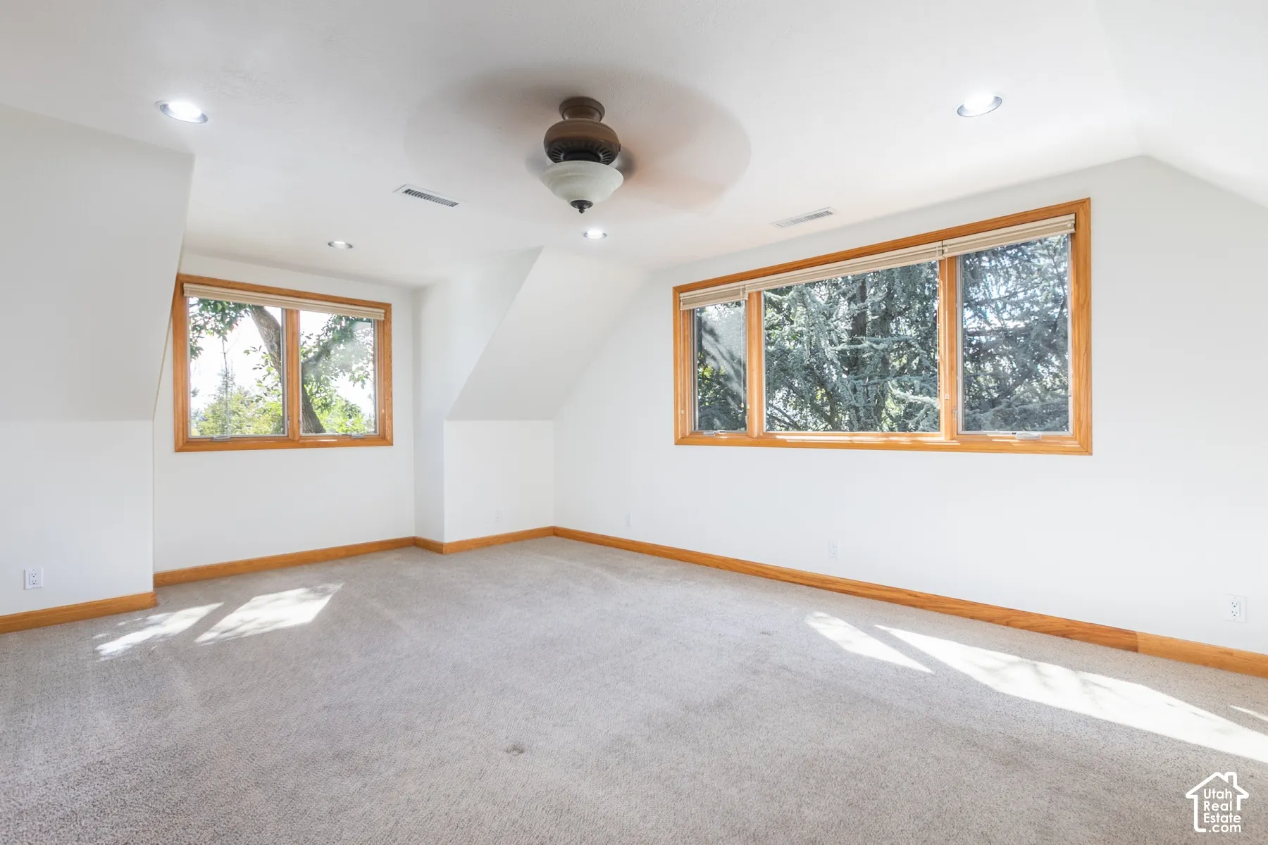 Recessed lighting, wood-trimmed windows, sloped ceilings, and a ceiling fan with light fixture
