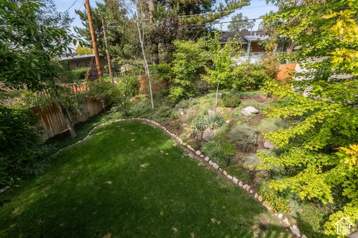 Expansive backyard featuring a manicured lawn, established landscaping, and a wooden perimeter fence