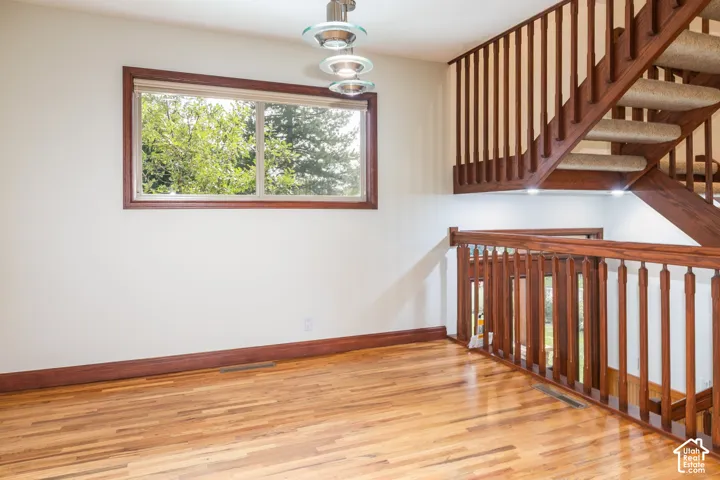 Hardwood flooring throughout, a large window with wood trim, and a contemporary pendant light fixture