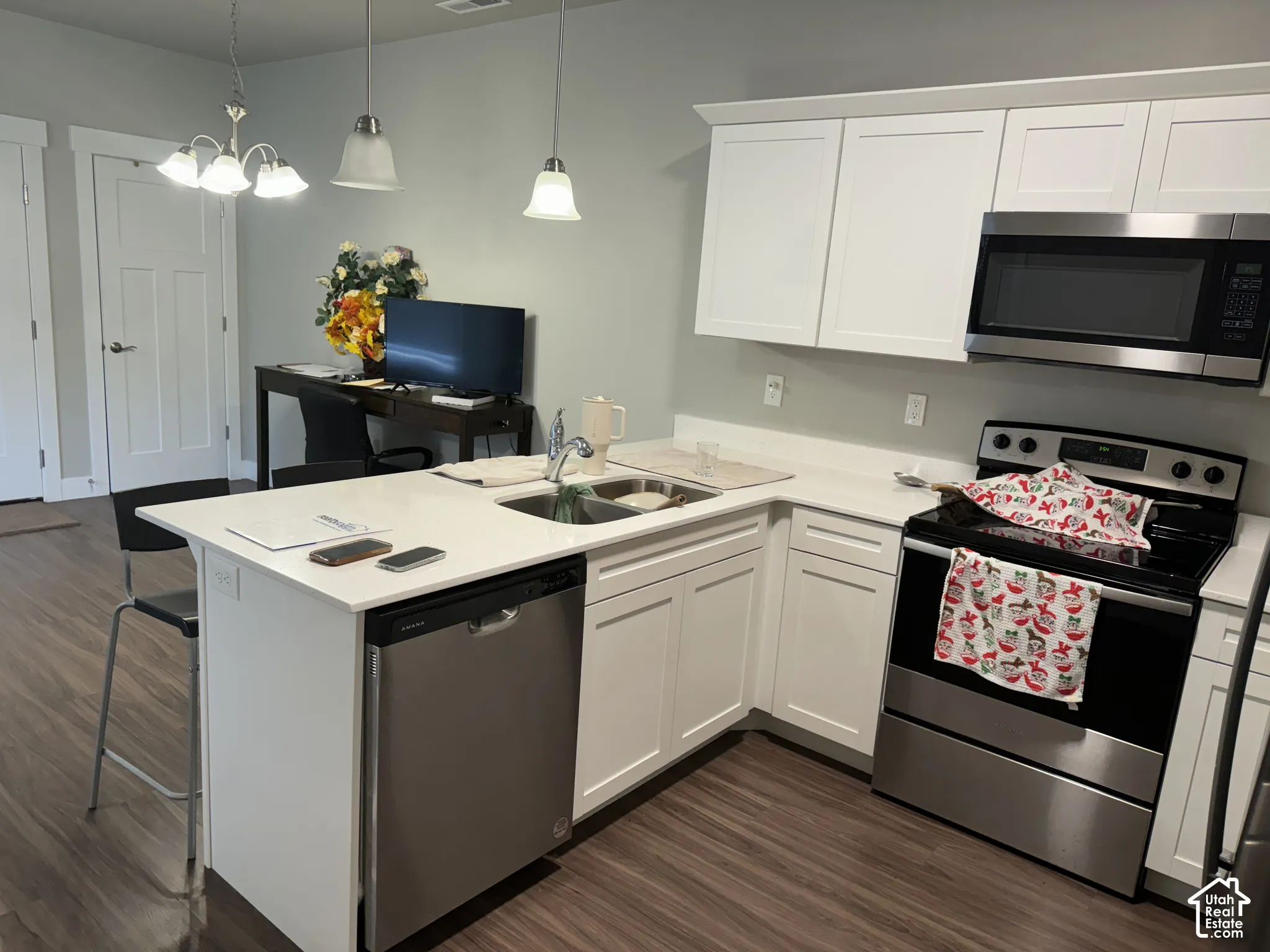 White cabinetry with a white countertop and stainless steel appliances, including an over-range microwave, range, and dishwasher