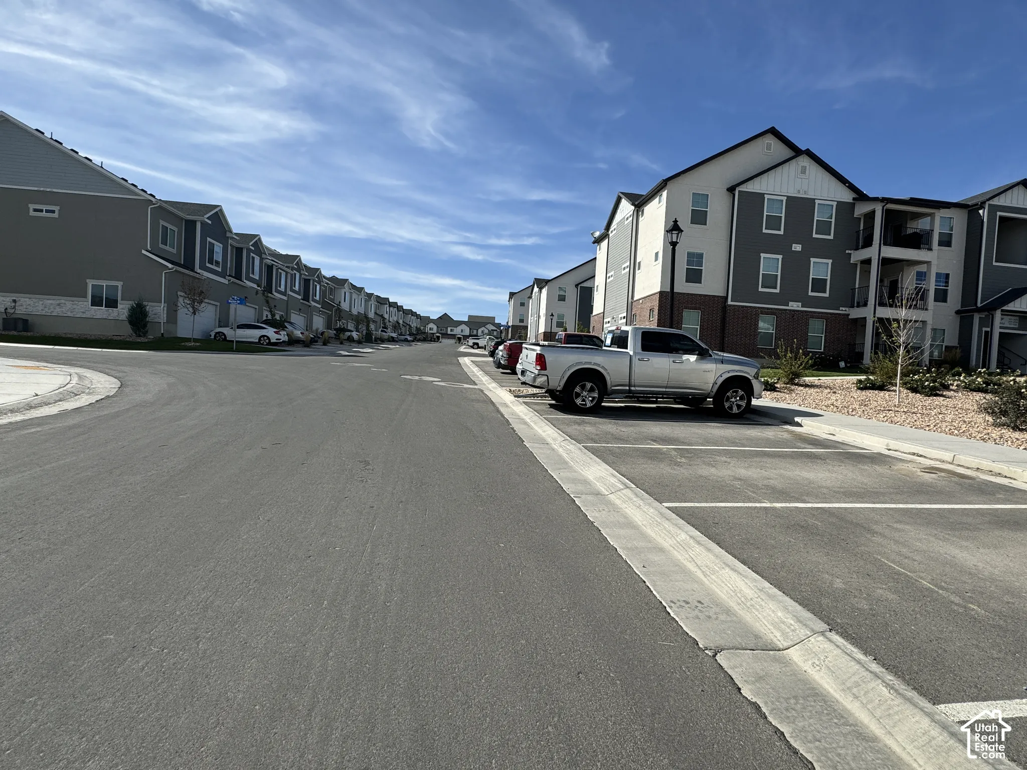 Street view showcasing residential buildings with gray siding, white trim, and brick accents