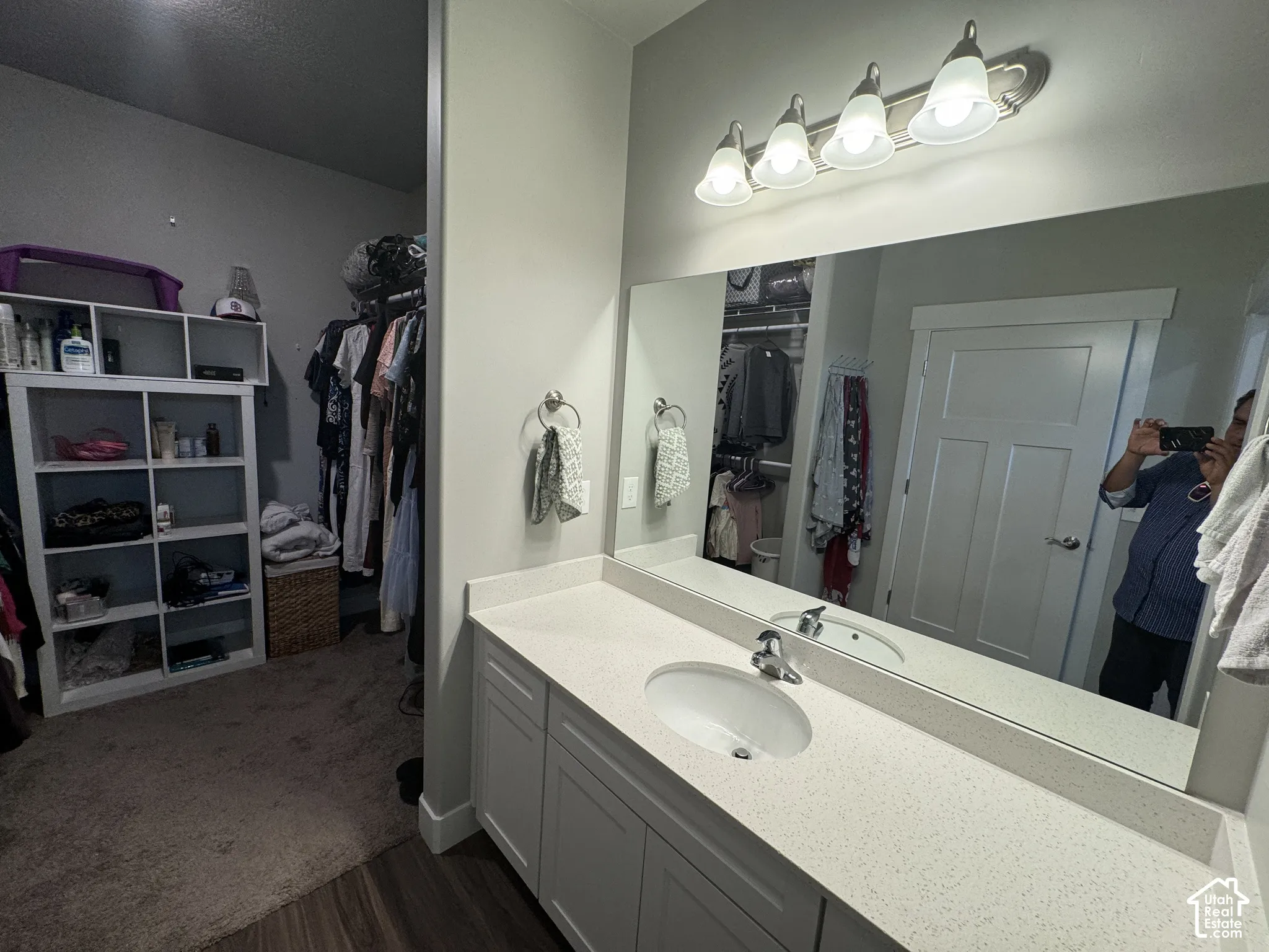 White cabinetry with brushed nickel hardware, expansive vanity mirror, integrated sink, and a four-light fixture