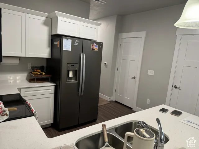 White shaker-style cabinetry with crown molding, light-toned countertops, a built-in stainless steel double sink, and wood-finish flooring