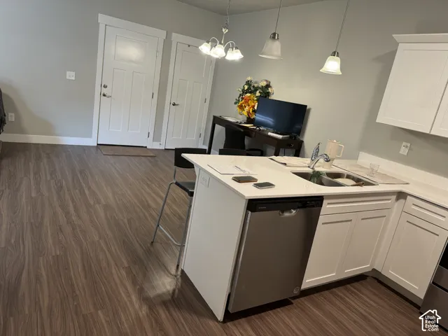 Kitchen featuring white cabinetry, light-colored countertops, stainless steel dishwasher, and a stainless steel sink