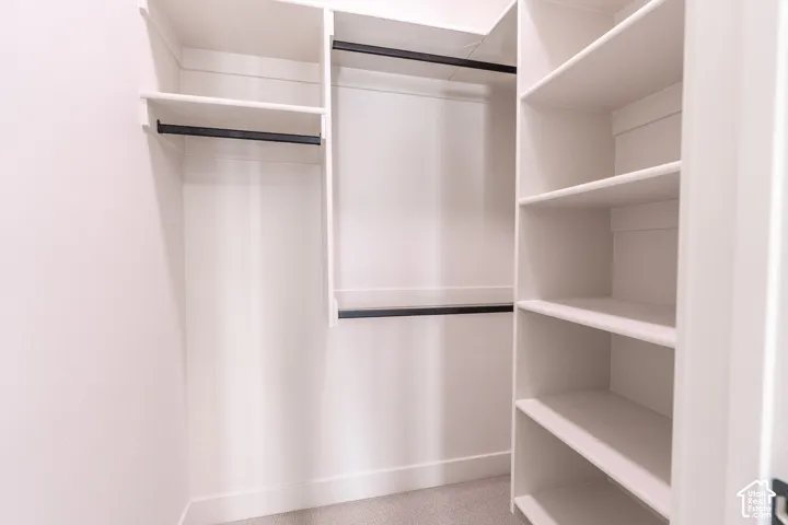 Built-in white shelving, integrated hanging rods, and light-toned carpeting
