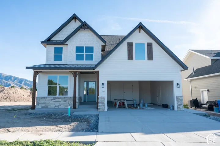 Contemporary two-story exterior with white siding, dark trim, stone veneer accents, wood posts, and a two-car garage