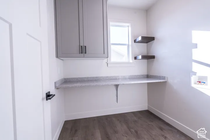 Upper cabinetry with matte black hardware, floating wood-finish shelves, a window, a built-in counter, and wood-finish flooring