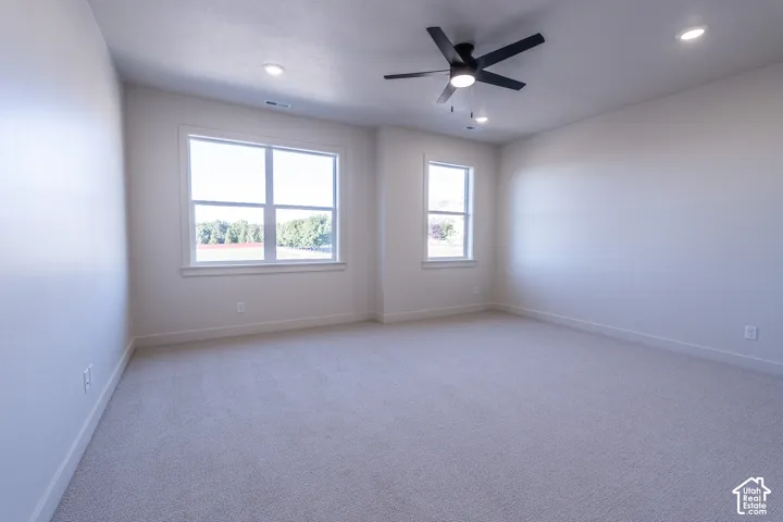 Wall-to-wall carpeting, multiple windows, recessed lighting, and a ceiling fan