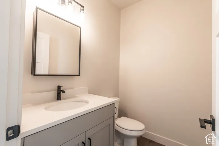 Vanity with light gray shaker cabinetry, white countertop, and matte black hardware