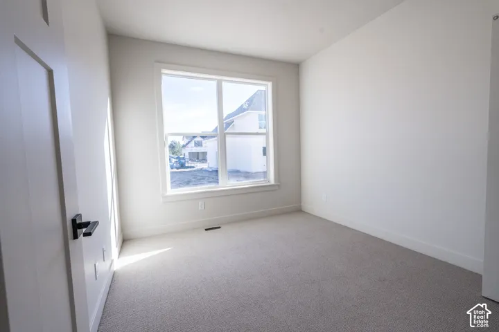 Neutral wall tones, carpeted flooring, large window with white trim, contemporary door, matte black hardware