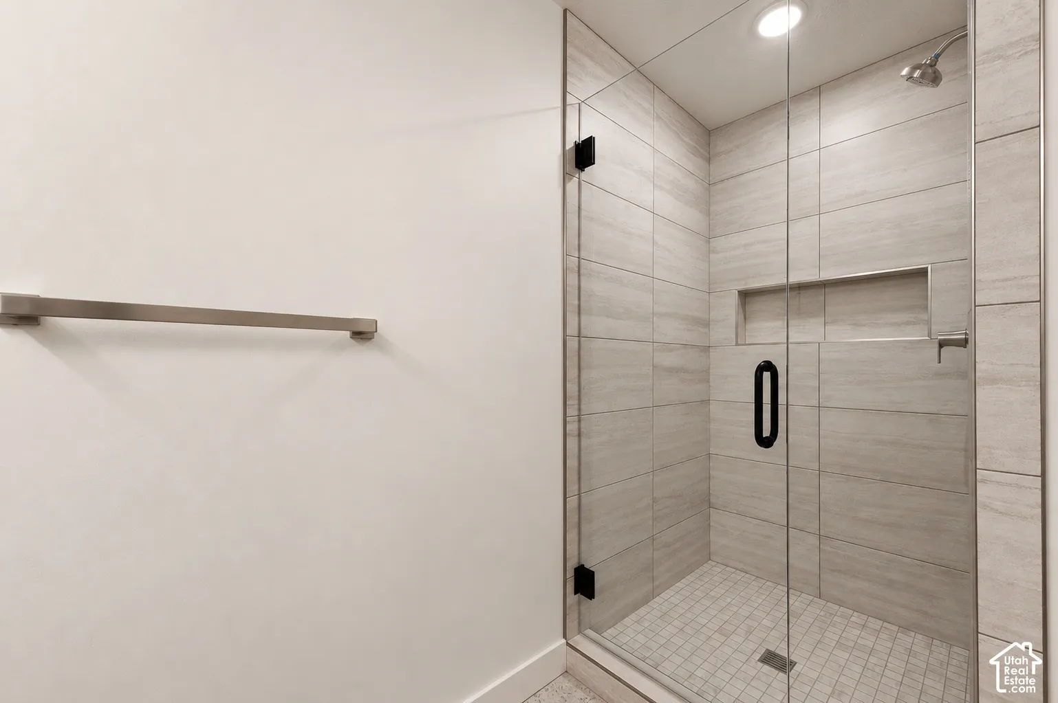 Glass-enclosed shower with tile surround, built-in recessed shelf, and integrated shower head