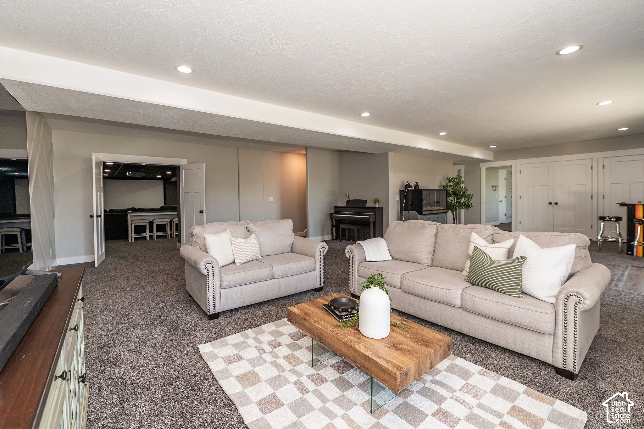 Recessed lighting illuminates the carpeted living area, featuring a double-door entry to an additional space