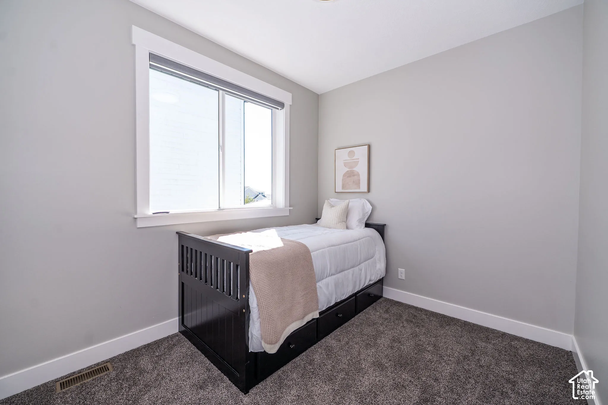 Wall-to-wall carpeting, light gray wall paint, and a large window with white trim