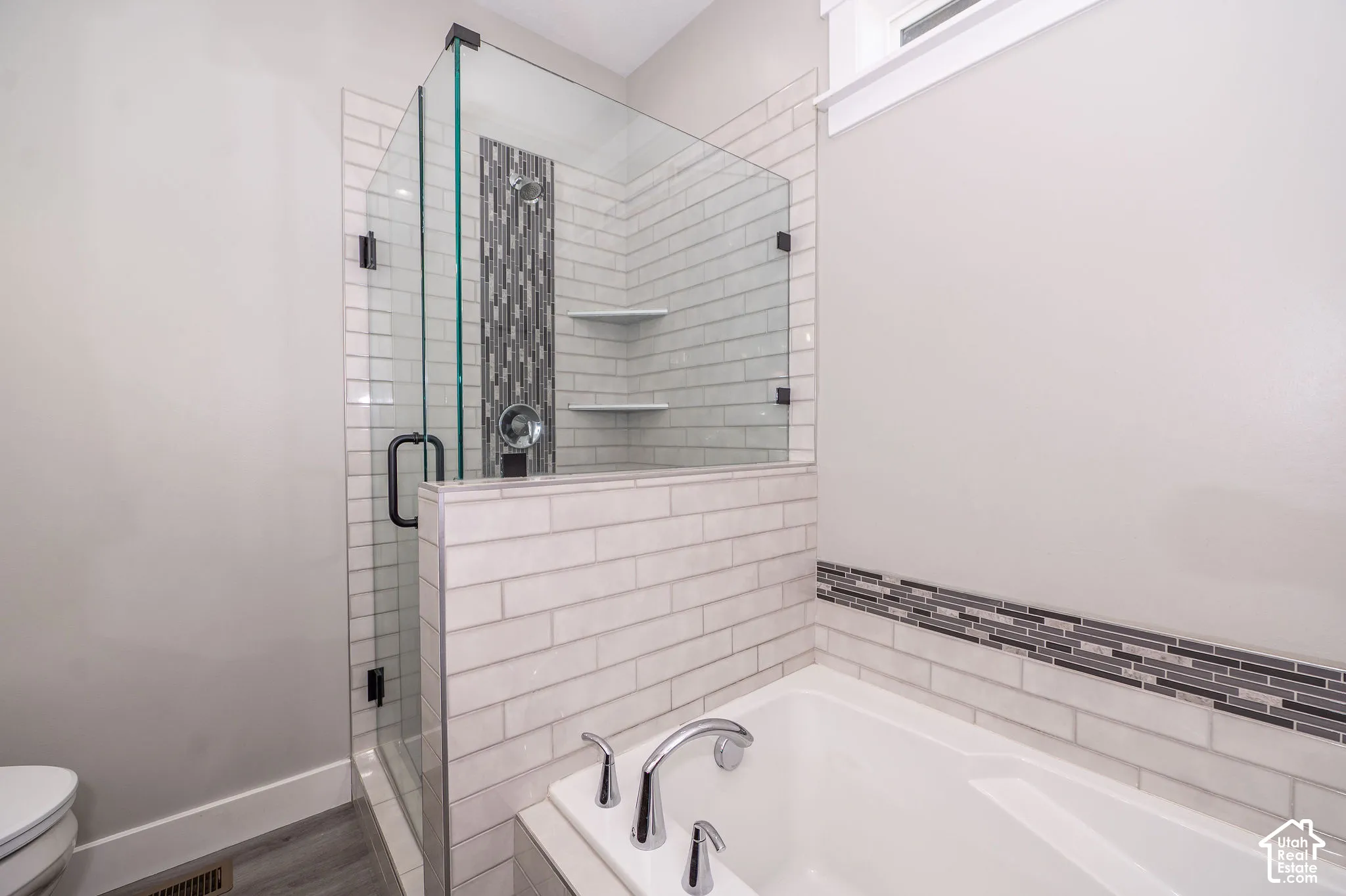 Walk-in shower with clear glass enclosure, subway tile surround, and built-in shelving