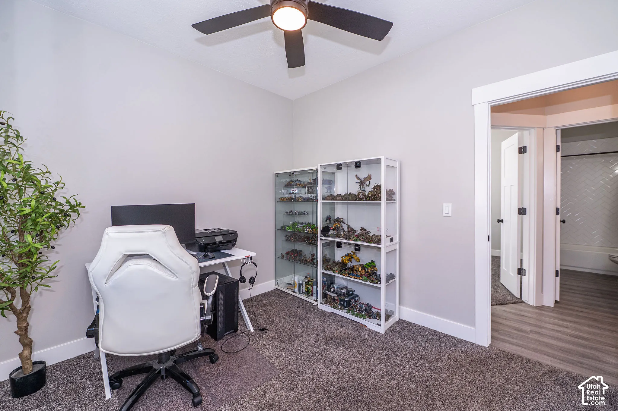 Neutral paint palette with carpeted flooring, featuring a ceiling fan, white trim, and a white interior door