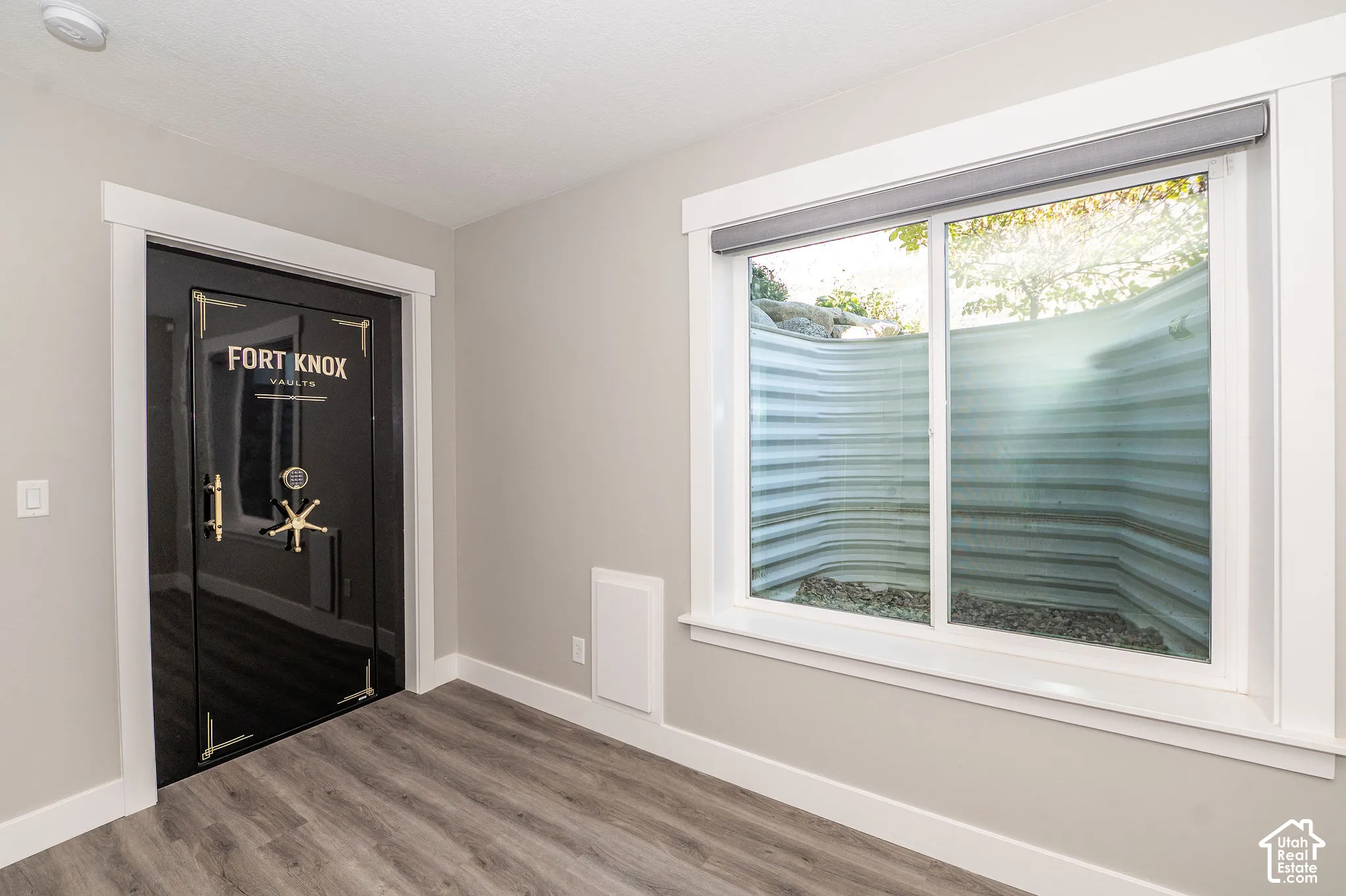Vault door with brass-finish hardware, wood-finish flooring, and a large window
