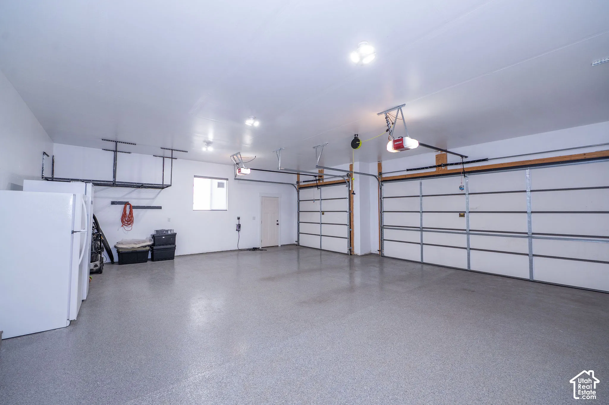 Expansive garage with durable epoxy flooring, two overhead garage doors, ample overhead lighting, and a single window