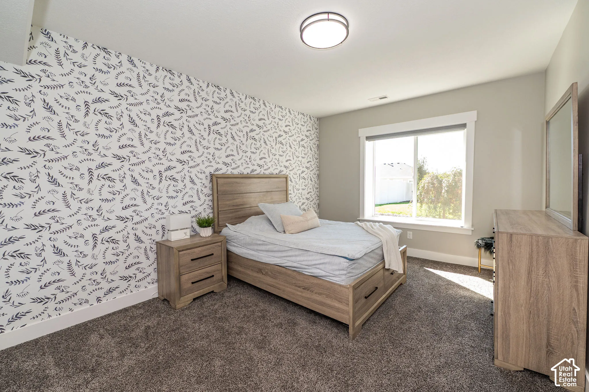 Textured accent wall, neutral wall paint, flush mount ceiling light, carpeted flooring, and a large window with a white frame