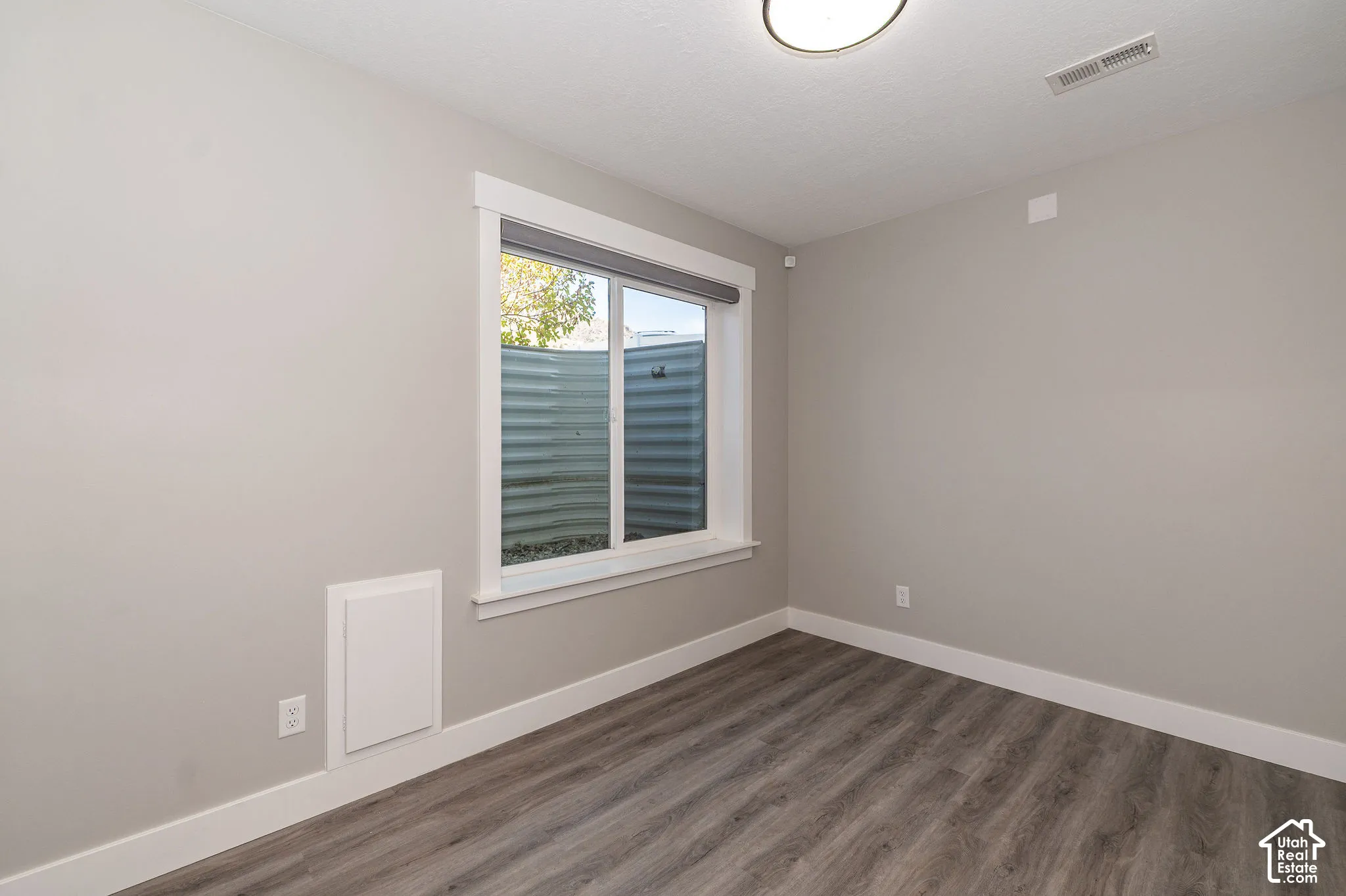 Wood-finish flooring, neutral wall tones, and a window with white trim