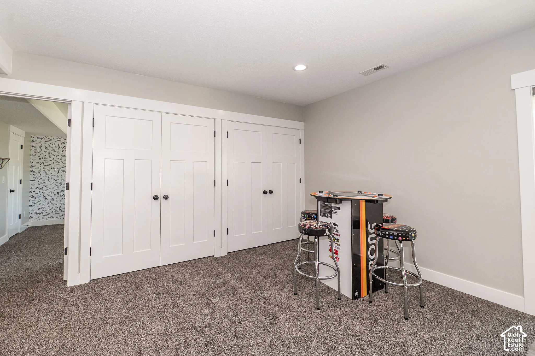 Recessed lighting, light gray wall paint, white trim, paneled doors with black hardware, and gray carpet flooring